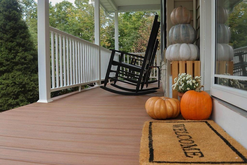 18. Add Rustic Porch Charm with Stacked Pumpkins and Rocking Chairs