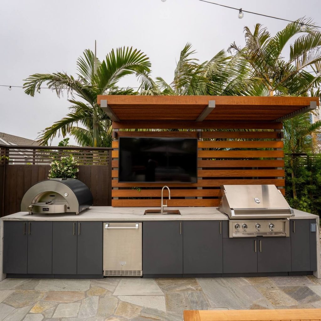 9. Contemporary Outdoor Kitchen with Pizza Oven and TV Wall
